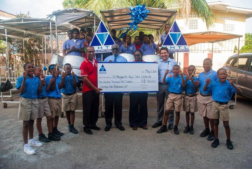  These talents from St. Margaret’s Boys’ Steel Orchestra, together with the Orchestra’s Manager, Kurt Abraham (left) and St. Margaret’s Boys Anglican Primary School’s Principal, Colette Perez (2nd from right), are all smiles as they receive a US$100,000 cheque donated by MHTL. Presenting the cheque are MHTL’s Chairman, Dr. Euric Bobb (2nd from left) and MHTL’s CEO, Dennis Patrick (right) 