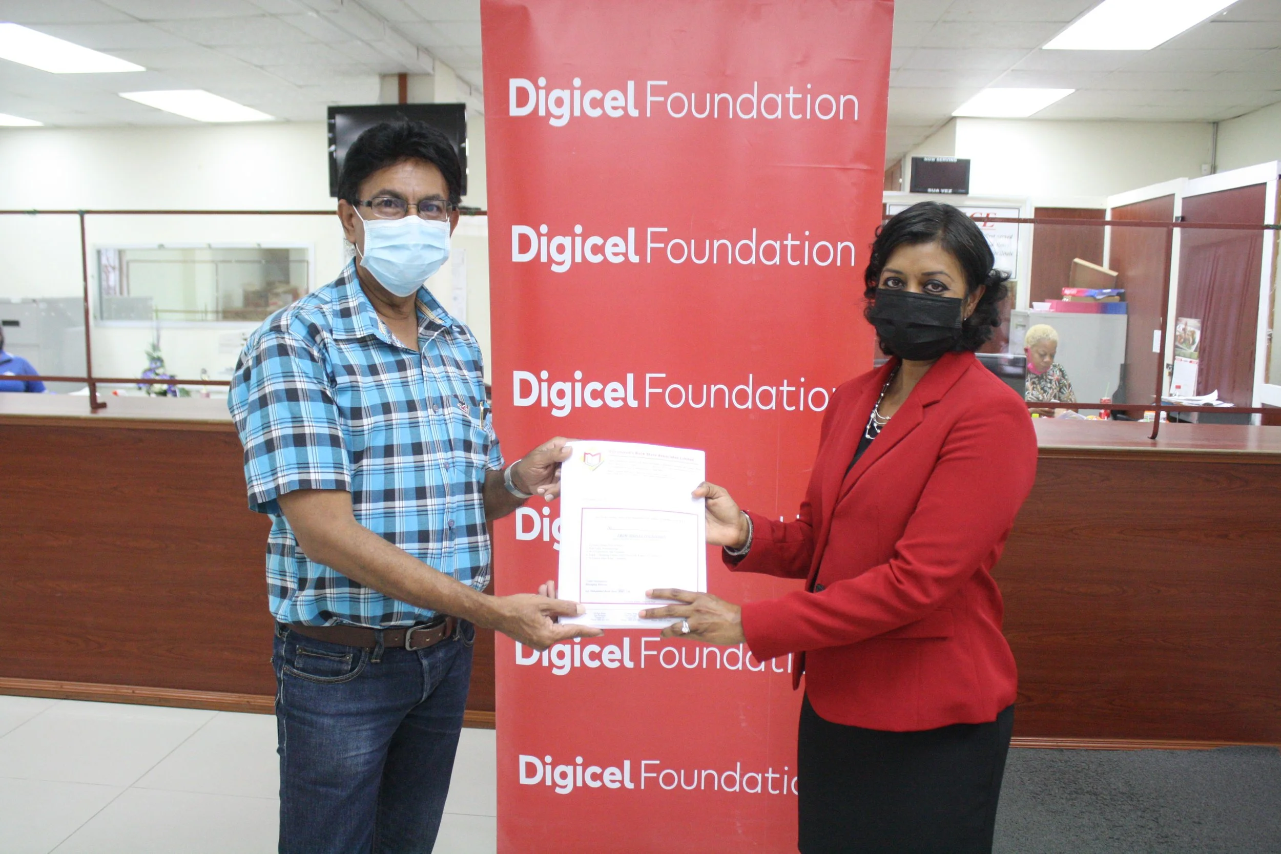   (L-R)  Councillor Ryaad Hosein for Les Efforts East/Cipero receives vouchers from Chairperson of the Digicel Foundation, Mrs Desha Clifford 
