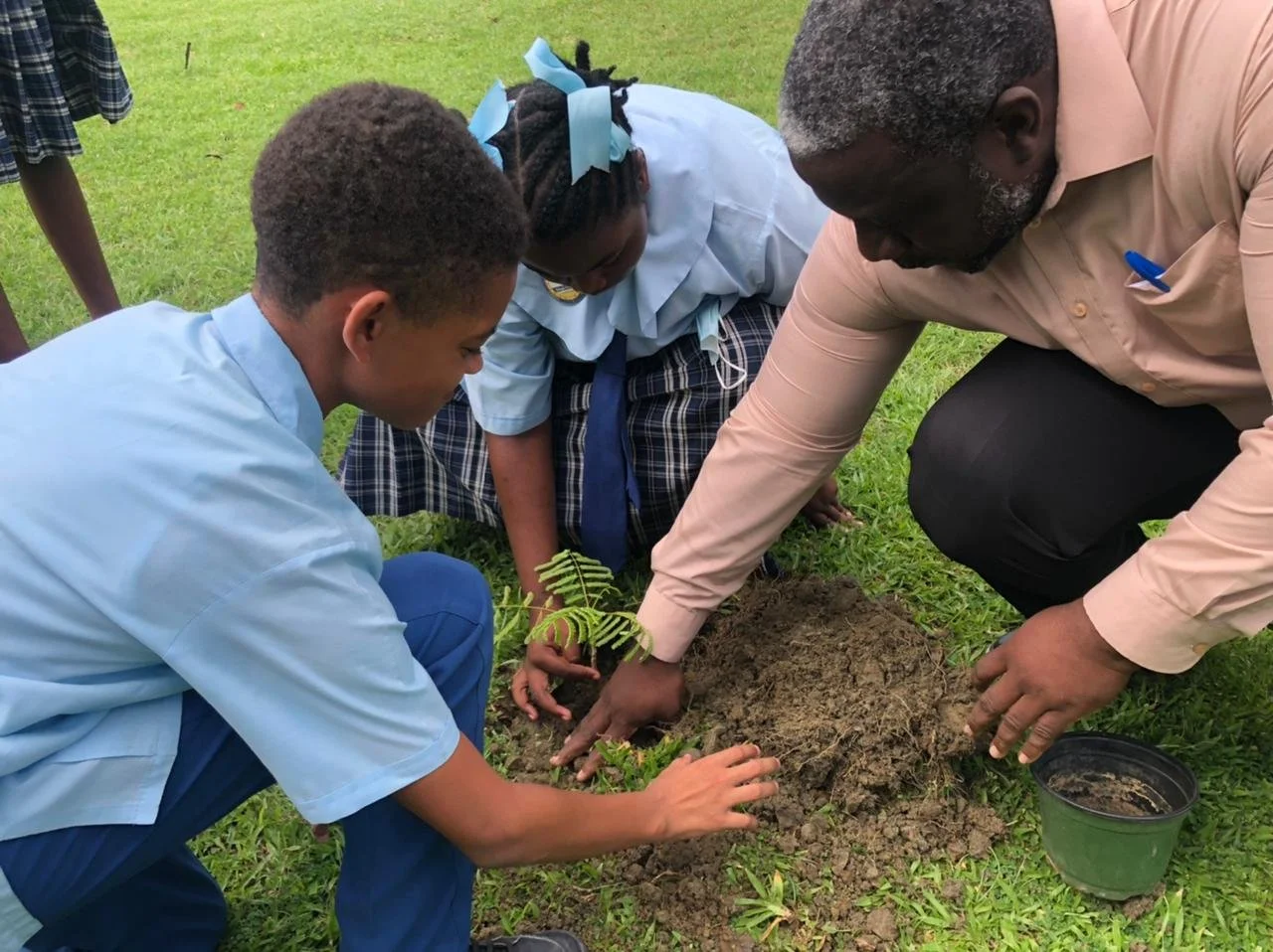 Speyside High School Environmental Science Teacher, Mr. Gerald Peters, and students from the Speyside High School Environmental Club participate in the tree planting activity on their school grounds.