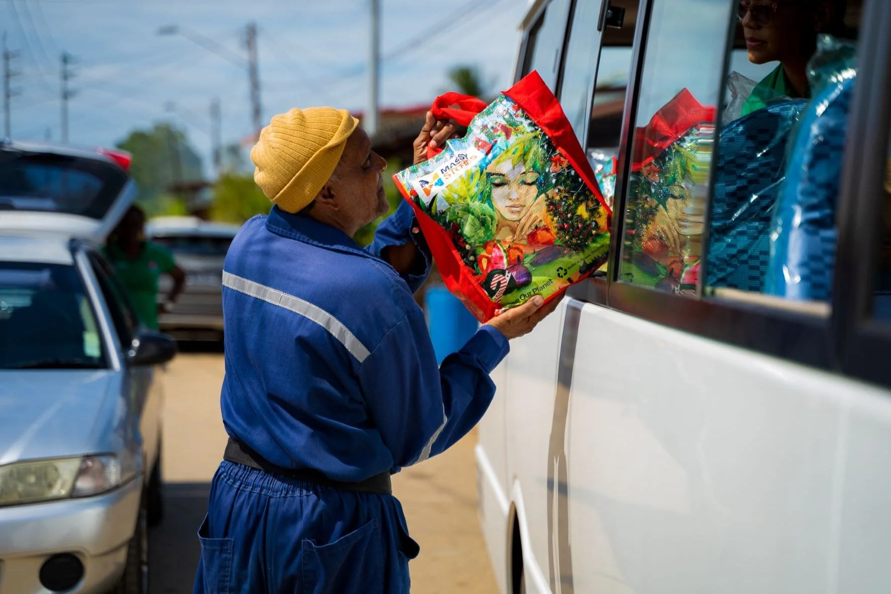 A resident from Bamboo Village receives one of the Massy hampers distributed during flood relief efforts.