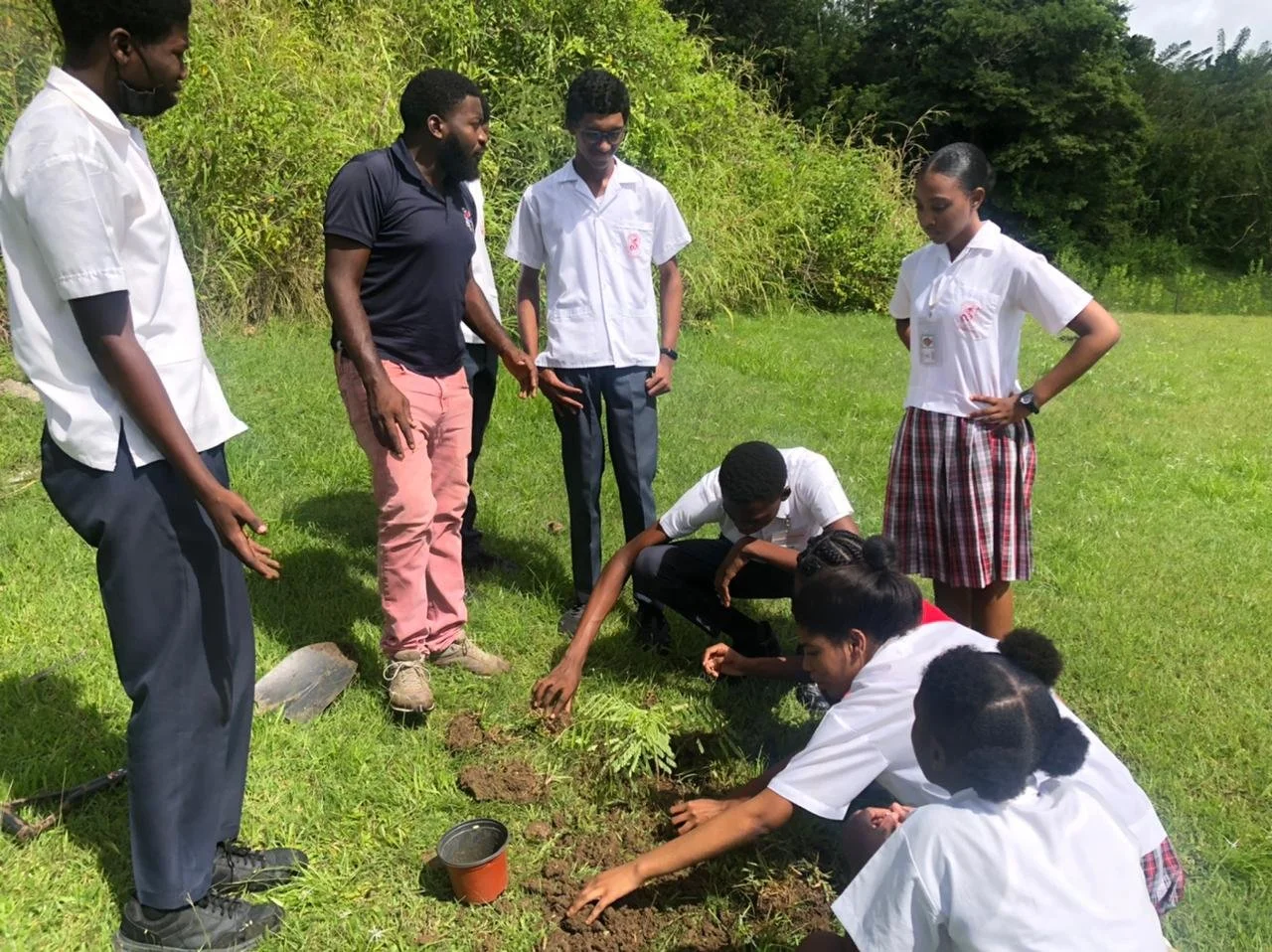 Mr. Wade Caruth, Agricultural Technician at Mason Hall Secondary, explains the benefits of planting the Flamboyant tree and guides his students in the tree planting initiative on school grounds.