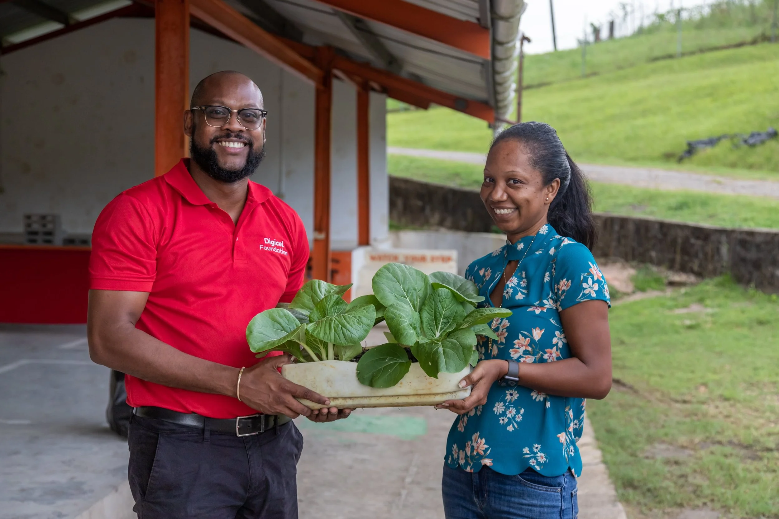   (L-R)  Digicel Foundation Board Member – Jerren Lewis and The Moruga 2050 Association for Sustainability Secretary - Kerneil Mitchell display one of the plants. 