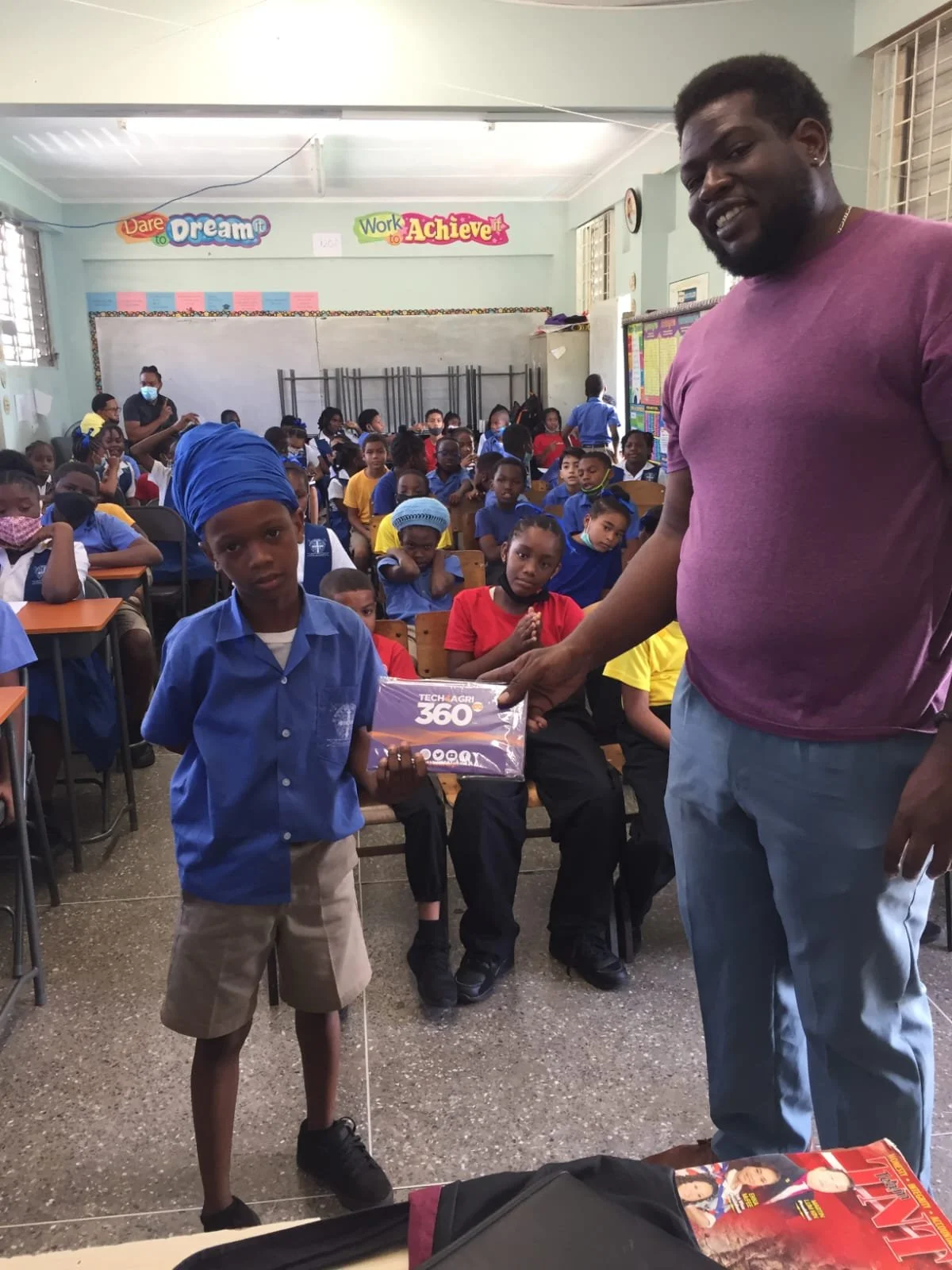 Tech4Agri Creator- Keron Bascombe (right) hands over one of the devices to a young student at St. Benedict’s.
