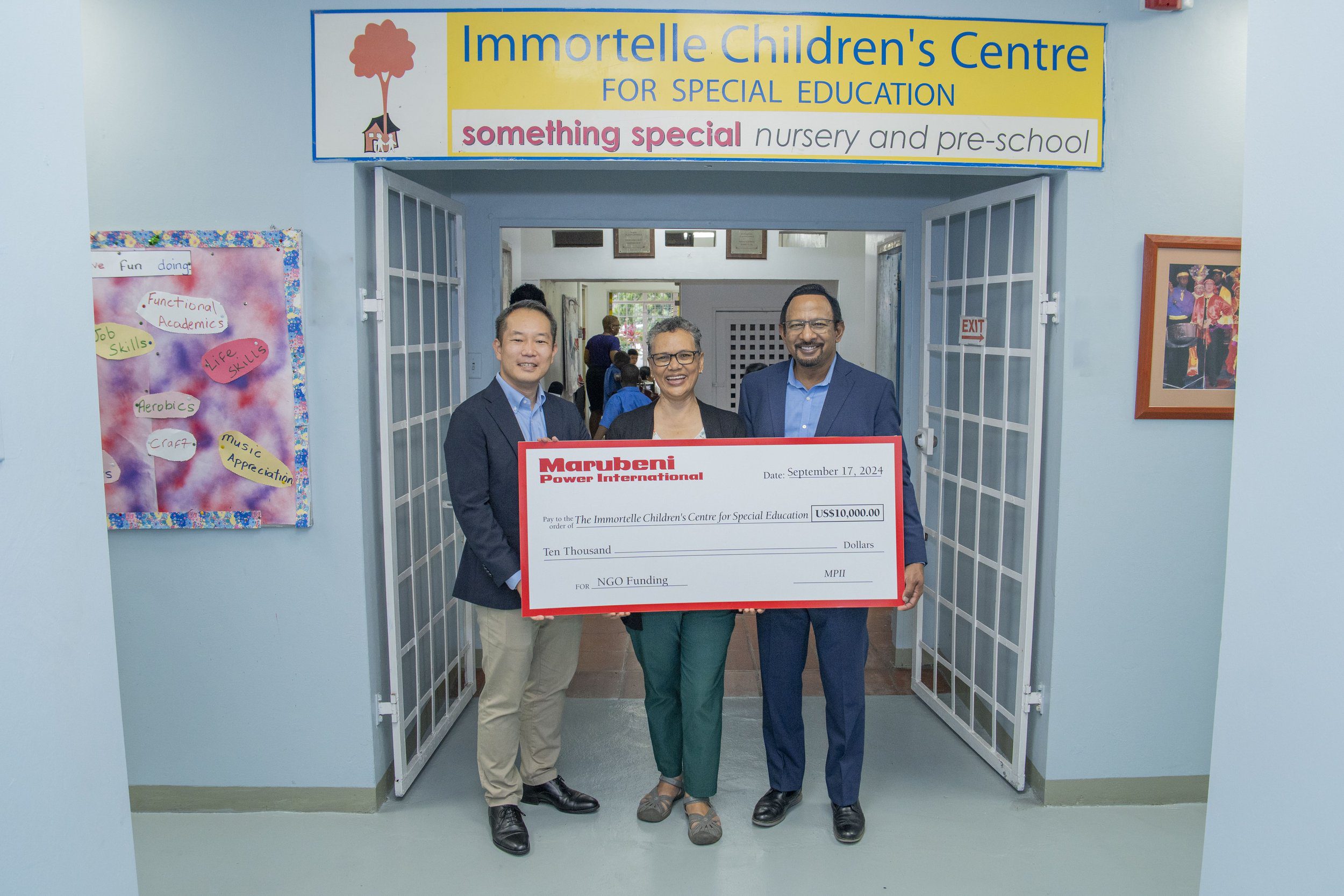 Keisuke Harada, Senior Manager, Marubeni Power International Inc (on the left), and Mo Majeed, COO/ Managing Director, Marubeni Power International Inc (on the right), present the Principal of Immortelle Children’s Centre for Special Education, Charlene Gittens, with a donation of US$10,000 on 17 September 2024.