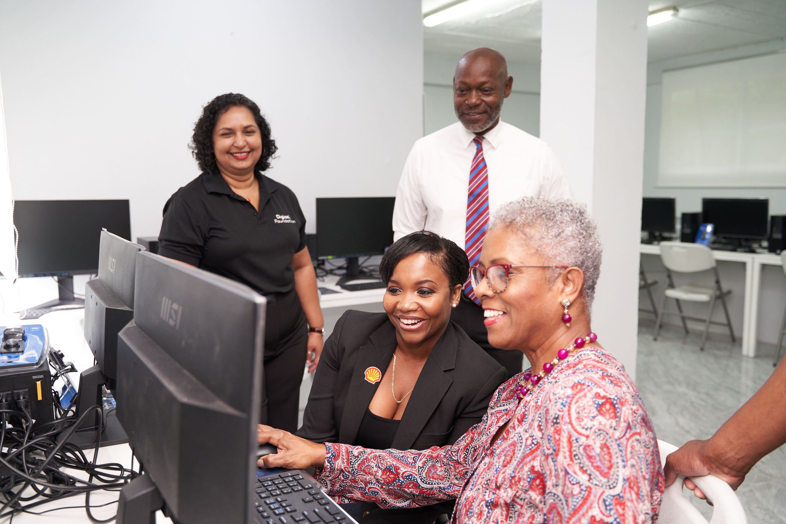  Wendy-Ann Wattie, Chair of Rebirth House Board (on the right), and Ryssa Brathwaite, Social Performance and Social Investment Advisor for Shell Trinidad and Tobago, test out the new computers at Rebirth House, as Digicel Foundation Director Trijata Maraj and Rebirth House Manager Aidan Thomas look on. 
