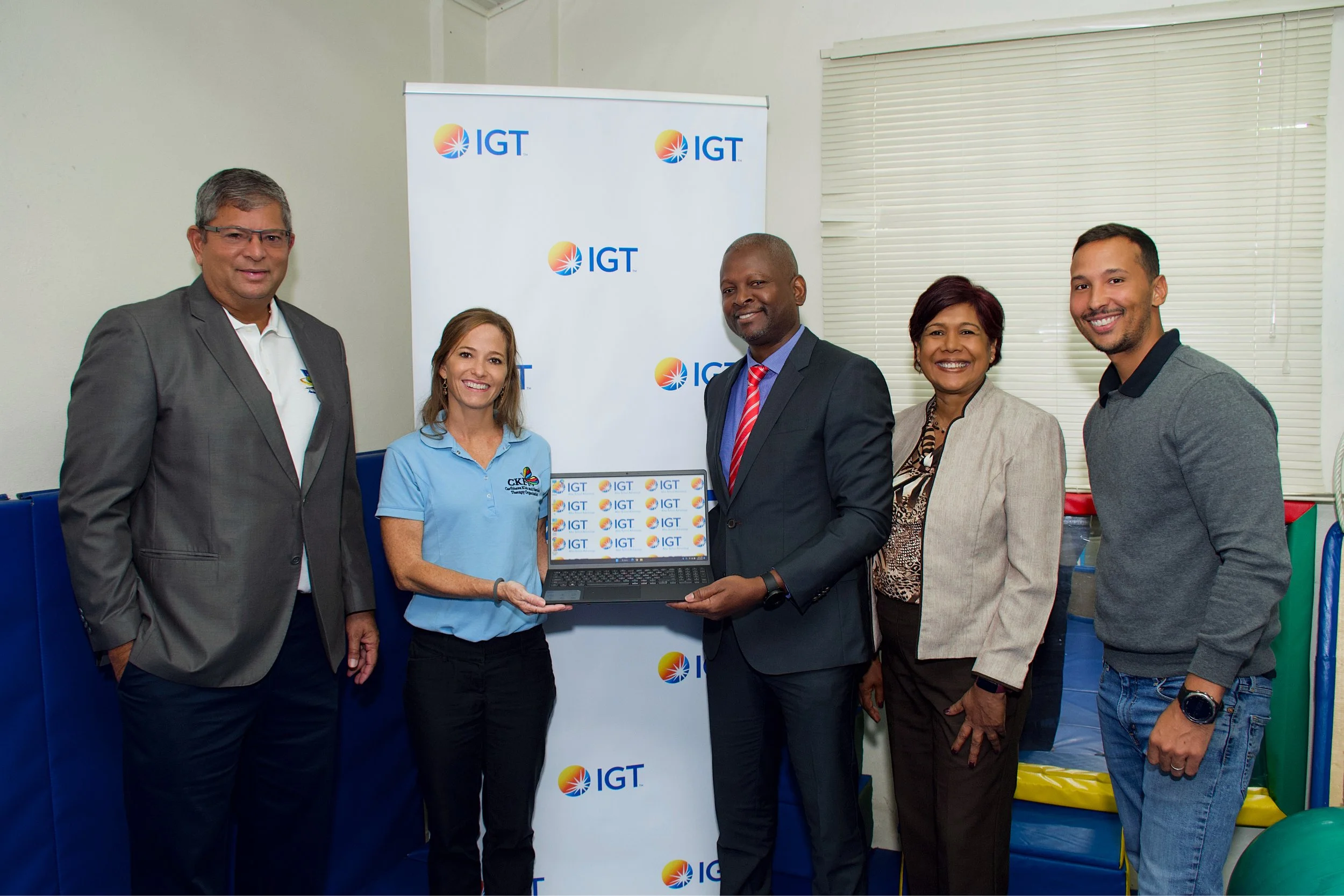 The Caribbean Kids and Families Therapy Organisation (CKFTO) receives new technology from the IGT After School Advantage Programme. From left to right: Roger Bolai, IGT Regional Director; Krista Hamel-Smith, CKFTO General Manager; Dexter Thomas, IGT General Manager; Shavindra Tewarie-Singh, IGT Senior Regional Human Resources Manager Caribbean; and Christopher Ristic, CKFTO Senior Registered Occupational Therapist.