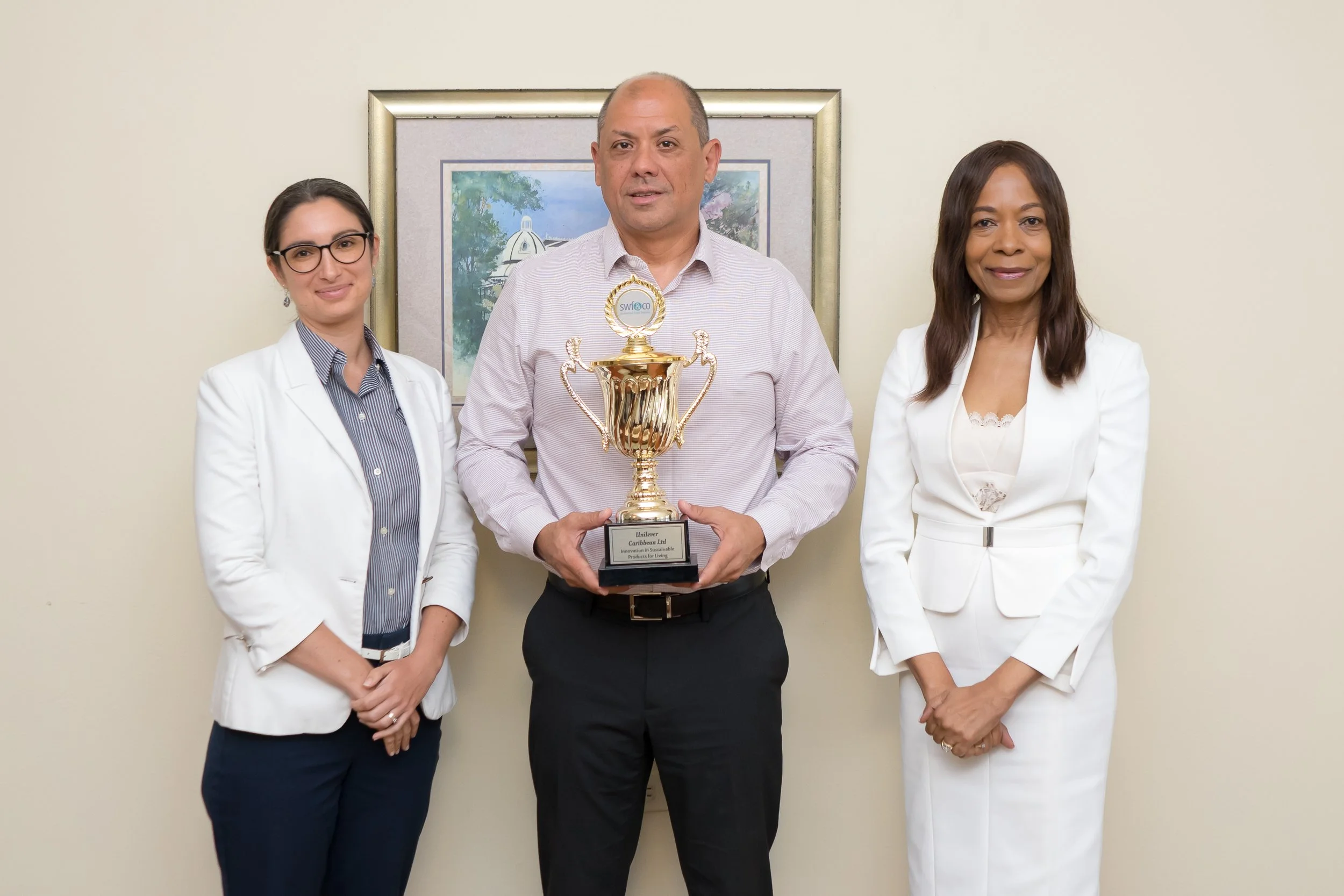 Sandra Welch-Farrell, SWF&CO CEO and Founder (right), and Anna Lucie-Smith, SWF&CO Communications Manager (left), present a Corporate Achievement Award to Jean-Marc Mouttet, Managing Director of Unilever Caribbean Ltd (centre).