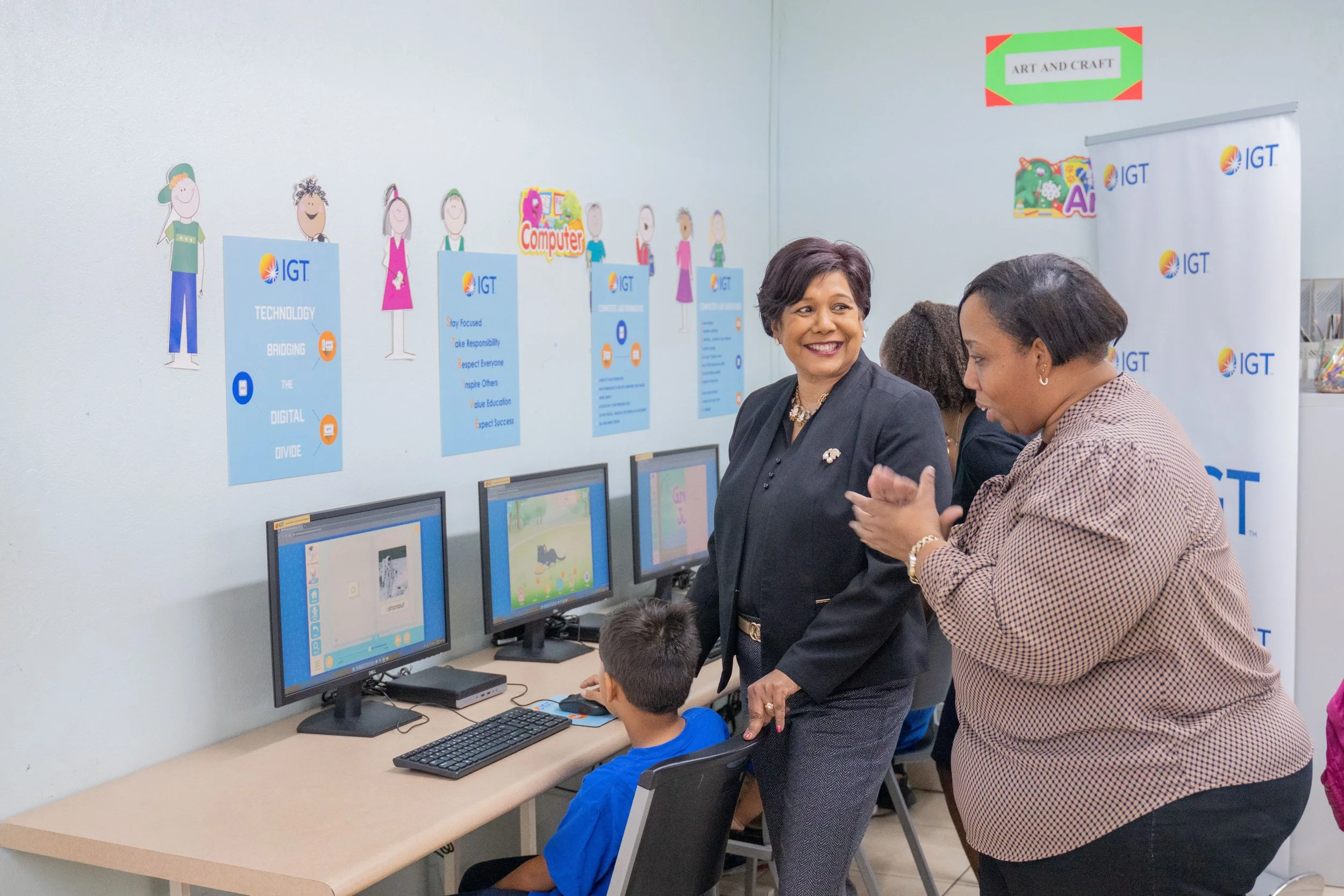 (L-R) Shavindra Tewarie-Singh, IGT’s People & Transformation Regional Senior Manager for the Caribbean, and Dale Bartholomew, Credo Foundation for Justice’s Administrator, lend encouragement to a student using one of the new desktops at the Credo Drop-in and Outreach Centre on Nelson Street, Port of Spain.