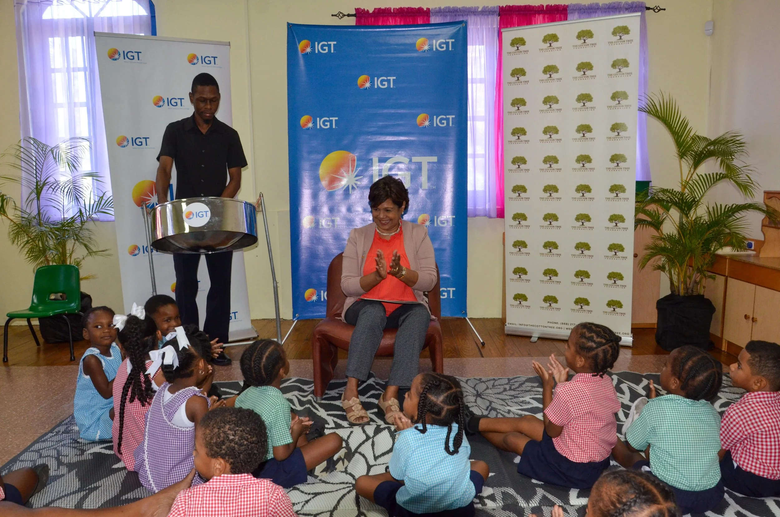  IGT P&T Regional Senior Manager for the Caribbean, Shavindra Tewarie-Singh, joins the Cotton Tree Foundation preschoolers as they clap and sing along to soca tunes played on the steelpan by Chavez Benjamin. 
