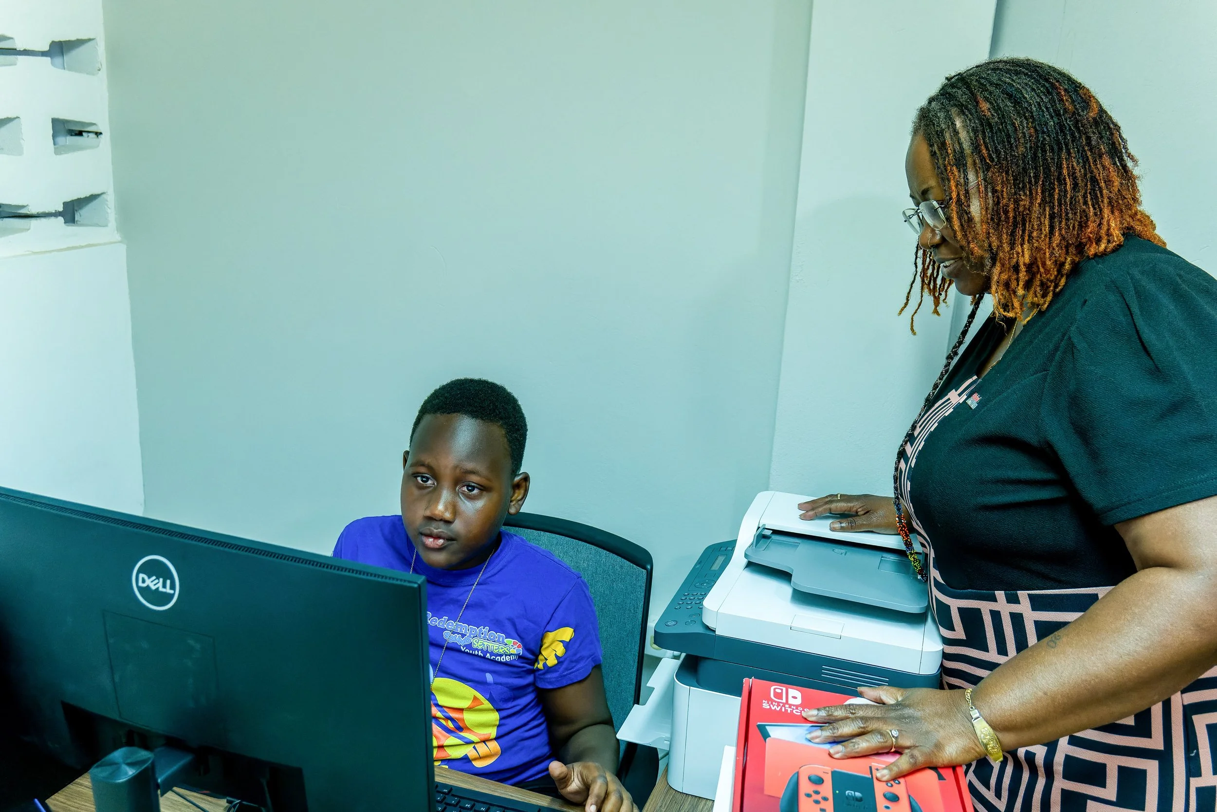  Digicel Foundation Director LaToya Gopaul assists a young band member using the new computers at Desperadoes Panyard on 25 March.    