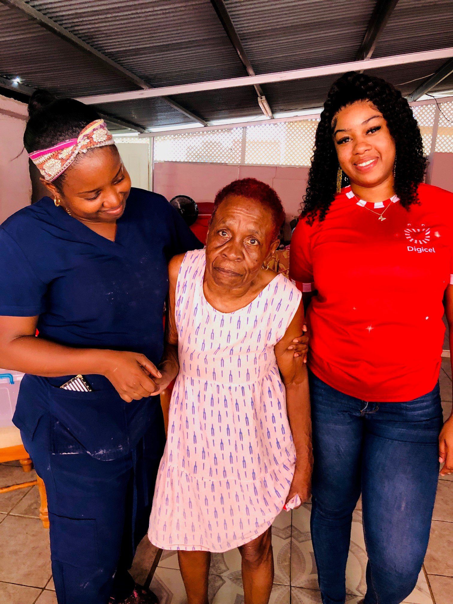 (From Left) Owner of Afeisha’s Home for the Aged, Afeisha Spencer-Mohammed pose with a lovely resident and Digicel Foundation Mobile Telesales Team member Cadesha Romany on Dec 24th.