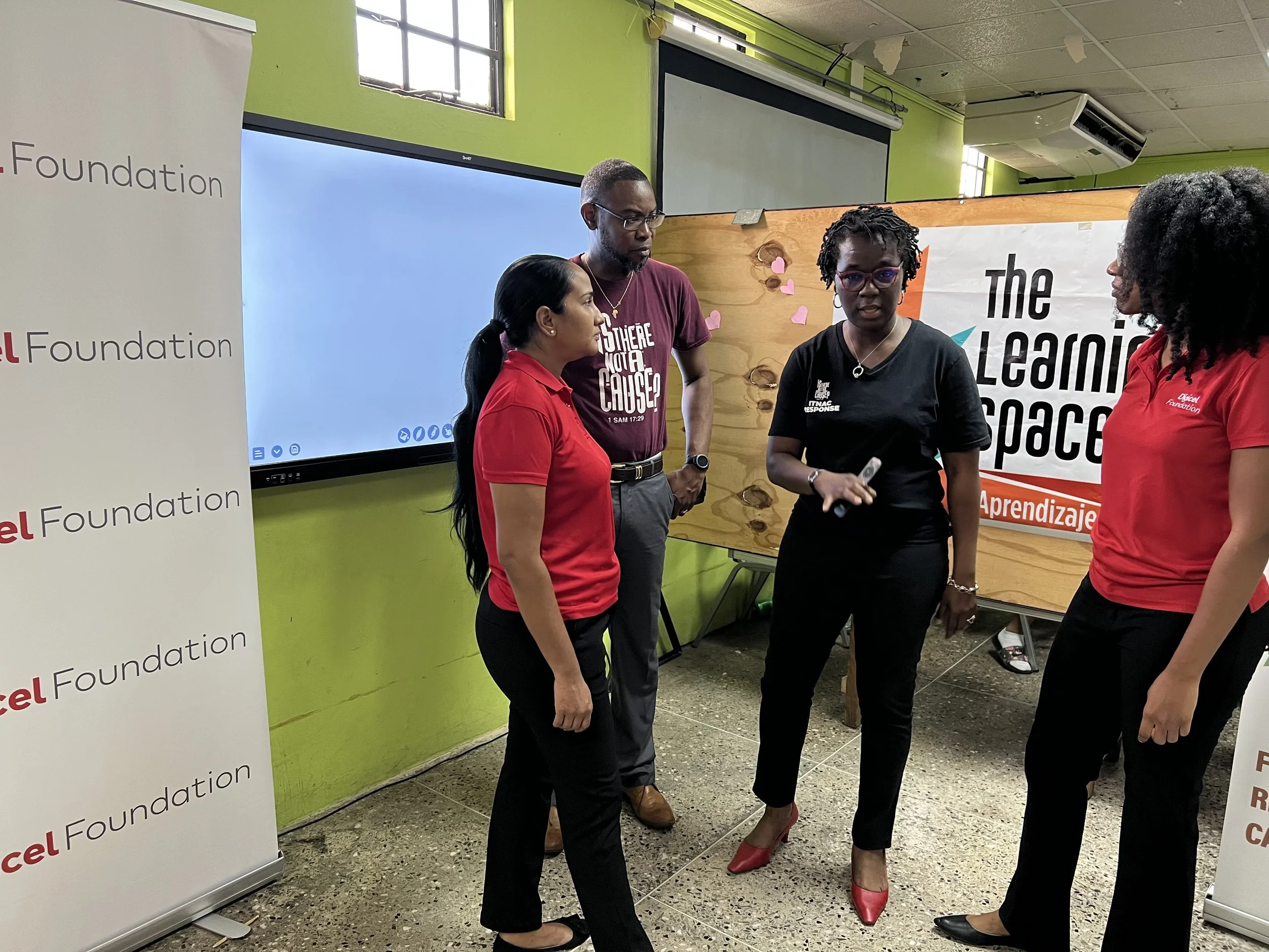 ( L-R) Diana Mathura, Project Officer, Digicel Foundation; Christopher Joseph aka ChrisJay of 98.1 FM; Avonelle Hector Joseph, Founder of ITNAC; and Misha Jackman, Finance Accountant, Digicel Foundation engaged in discussion on the use of the smart board in the learning space for migrant children at ITNAC’s The Love Centre.