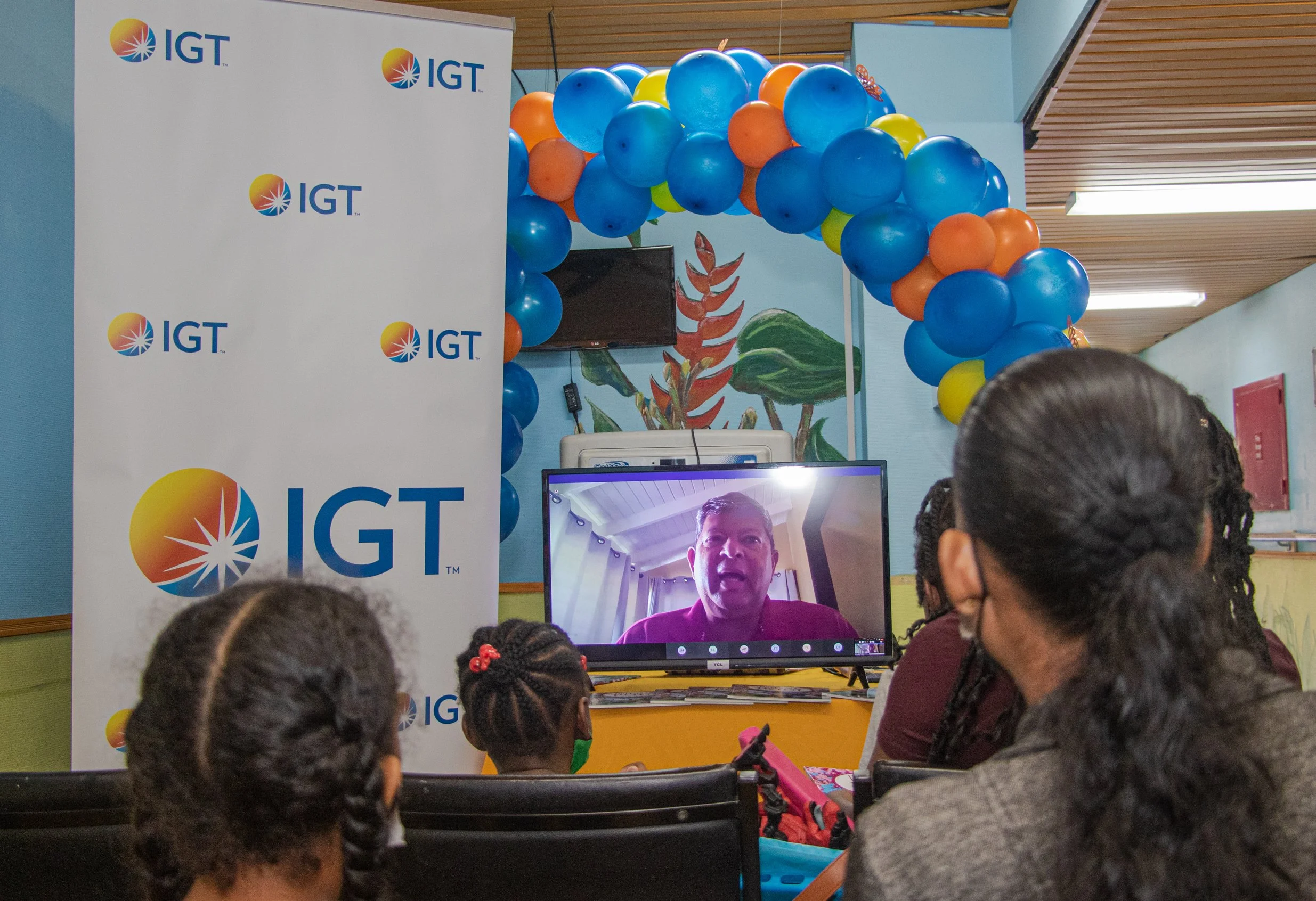 Patients of the pediatric oncology clinic and their parents were glued to the screen while IGT Country Manager Roger Bolai (shown on screen) read aloud from the local children’s book Petra and the Poui, written by Phillip Simon.