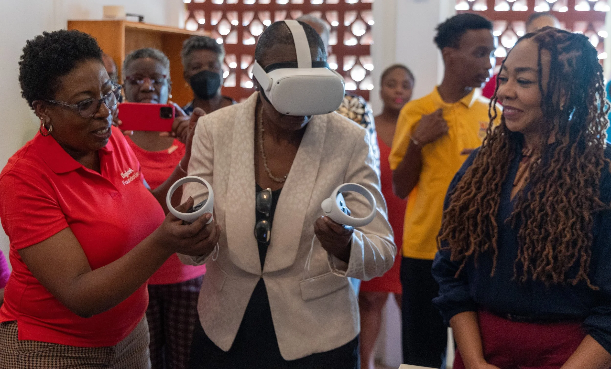  - Dianne Baker-Henry, Administrator, Division of Education Research and Technology (Centre) uses the virtual reality technology in the innovation lab at Happy Haven school, with support from Natalie-Anne De Silva, Digicel Foundation Project Consultant (left), and Penny Gomez, Digicel Foundation CEO (right). 