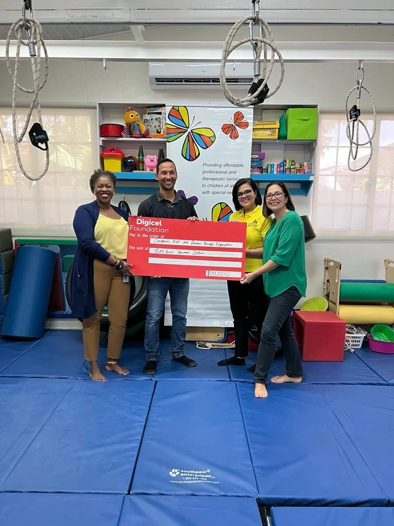 Digicel Foundation Head of Operations Cindyann Currency (far left) presents a cheque to CKFTO Vice-Chair Sofia Figueroa-Leon (far right) to support their programme to diagnose children with Autism Spectrum Disorder (ASD).