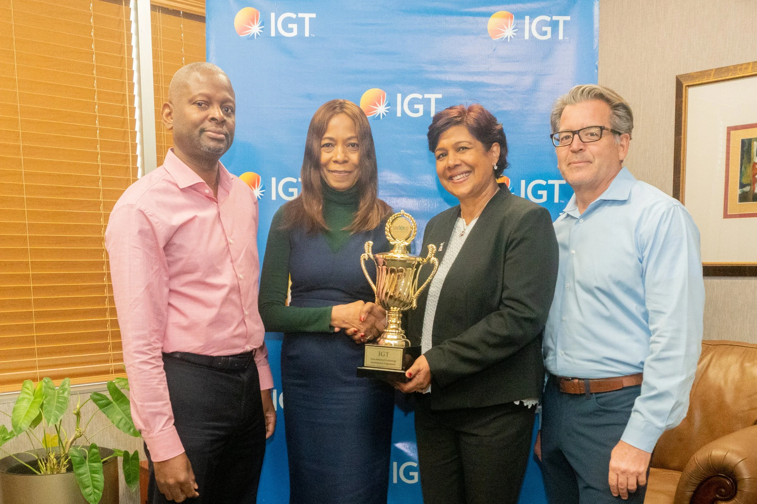  P&T Regional Senior Manager (Caribbean) Shavindra Tewarie-Singh (centre right) receives a SWF&CO Corporate Achievement Award from CEO and Founder of SWF&CO Sandra Welch-Farrell (centre left), as IGT Vice President Global Government Relations & U.S. Business Development Michael Mello (right) and Deputy Country Manager of IGT in Trinidad and Tobago Dexter Thomas (left) look on. 