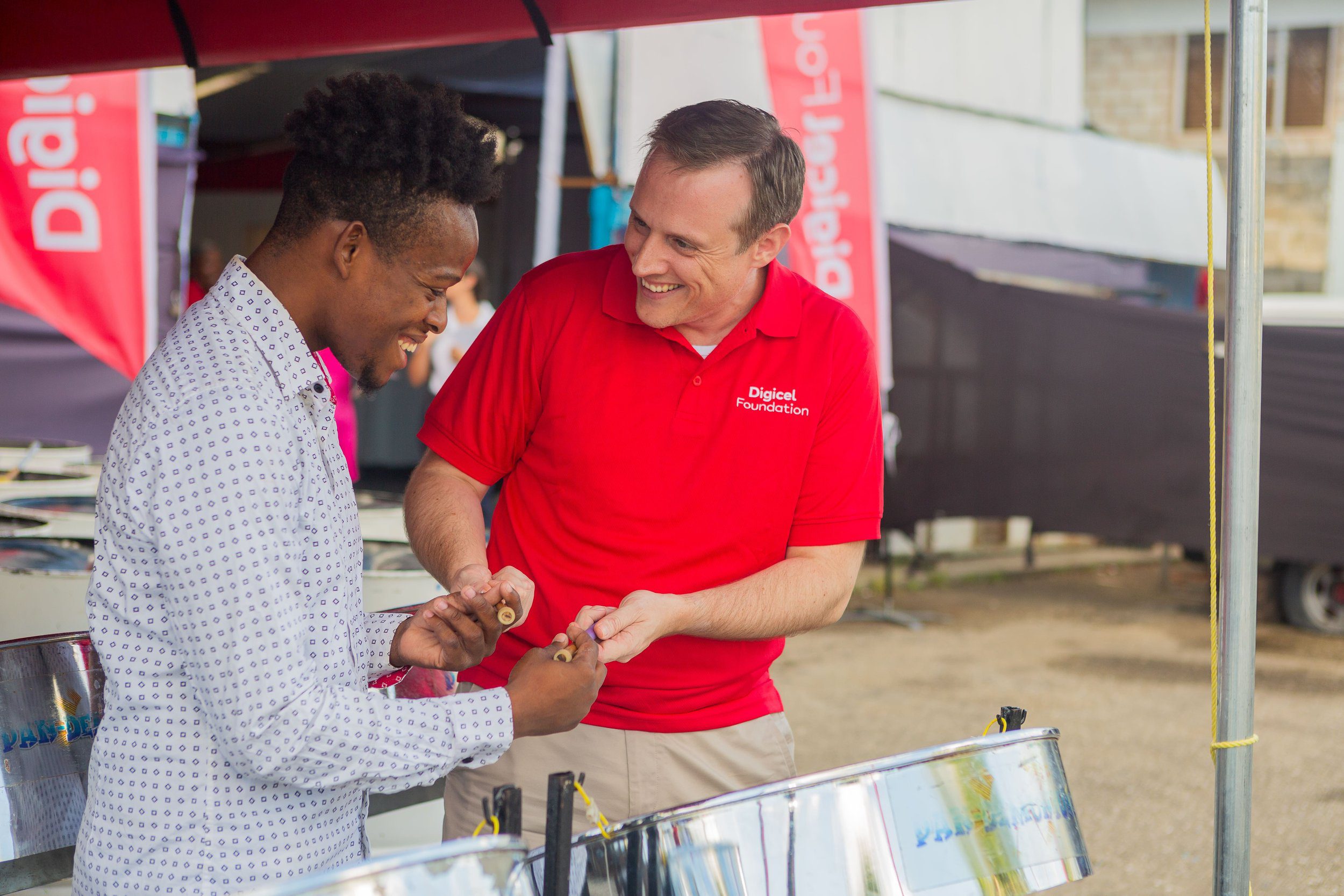 Abraham Smith, CEO of Digicel Trinidad and Tobago and Board Director of the Digicel Foundation (on the right), gets a quick pan lesson at Pandemonium Panyard in Belmont at the launch of the Digicel Foundation’s Technology in Education Centres on Wednesday 28 February 2024.