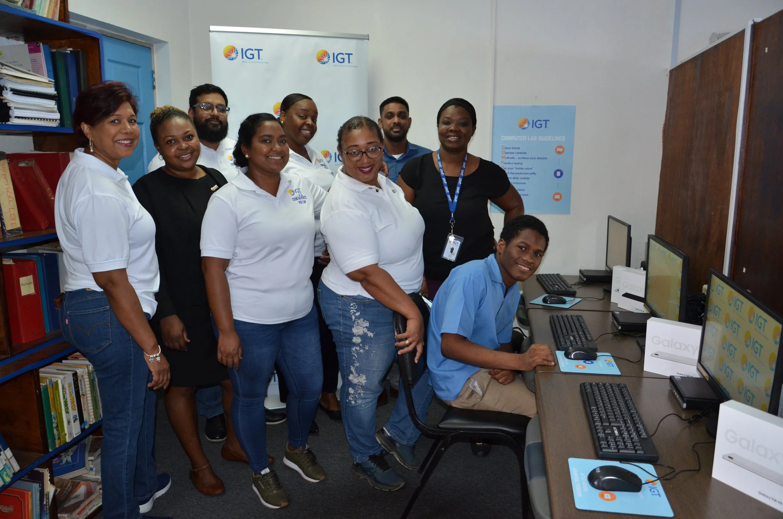 The IGT volunteer team stand behind a student and the new desktops that the team just installed at the Immortelle Centre on 24 May.