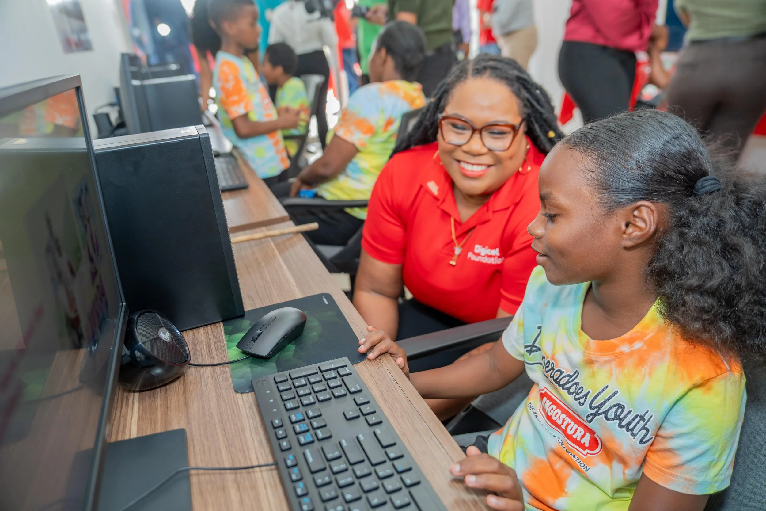  Digicel Foundation Director LaToya Gopaul assists a young band member using the new computers at Desperadoes Panyard on 25 March.    