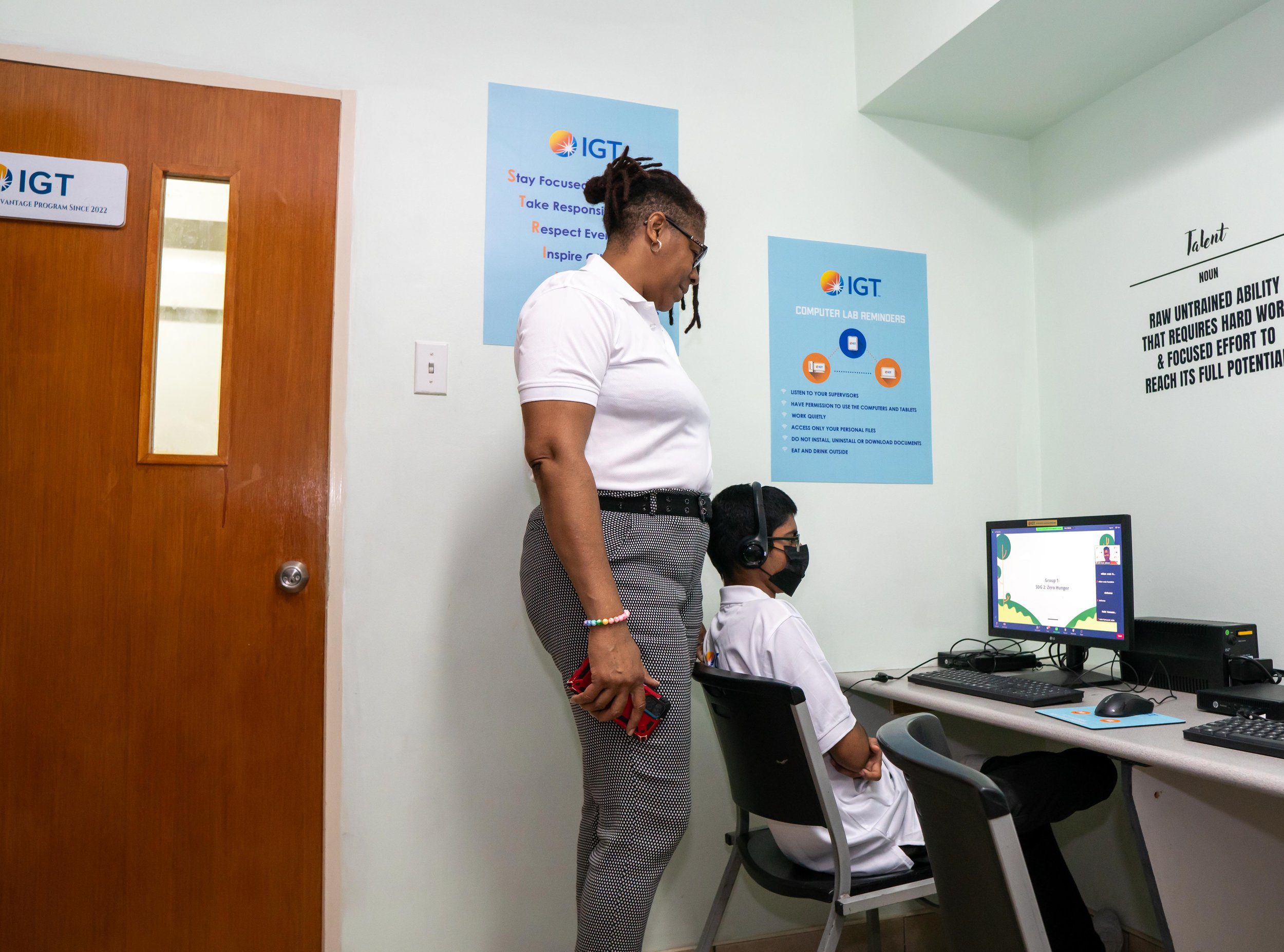 Keeping him on track! Nicole Phillip, Credo Boys Developmental Centre Coordinator, supervises a student during the third virtual IGT Coding and Robotics Rock! Camp, 17 - 28 July.