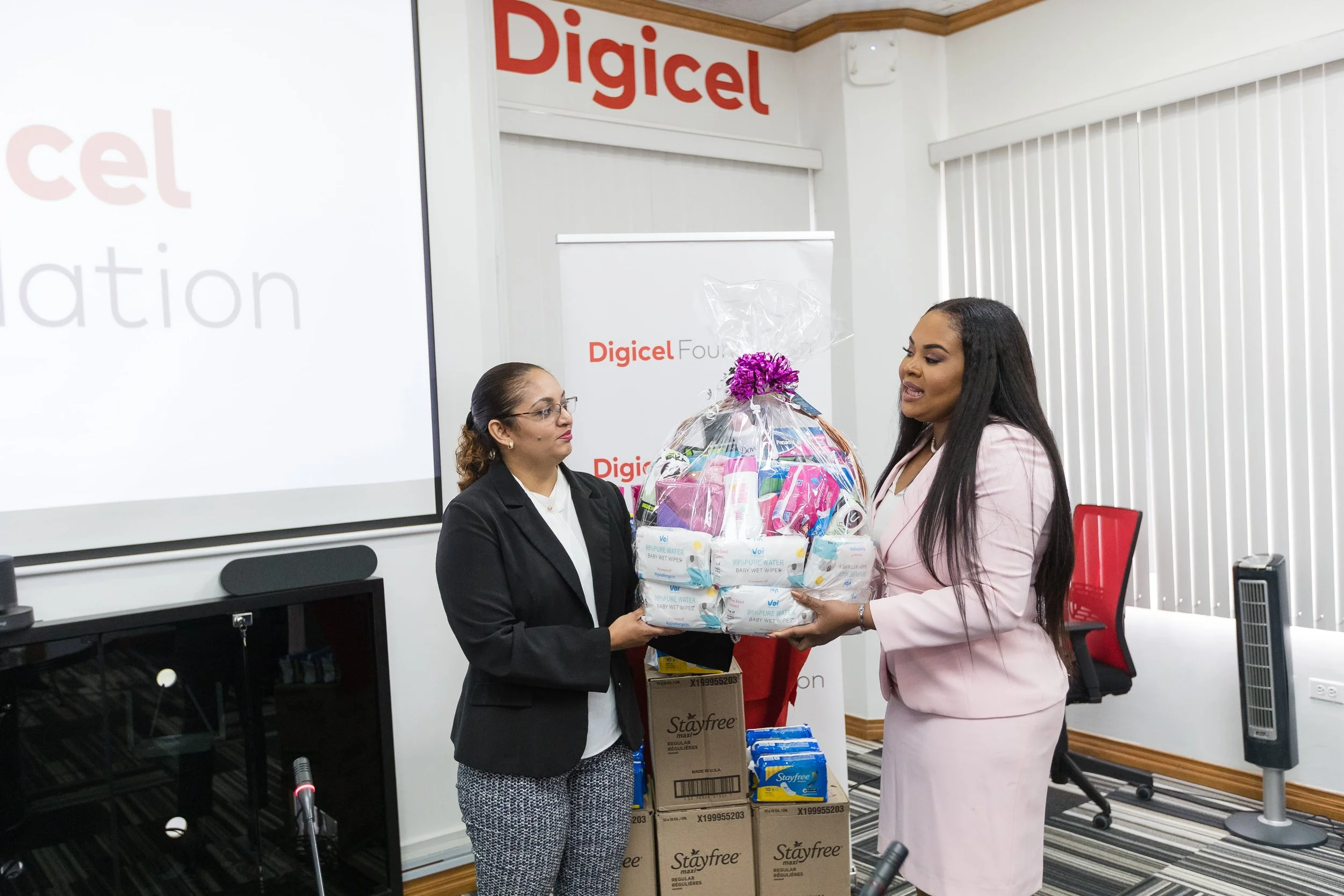 (L-R) Digicel Foundation Board member Bibi Mohammed accepting the hamper of feminine products donated by The Hon. Shamfa Cudjoe, Minister of Sport and Community Development