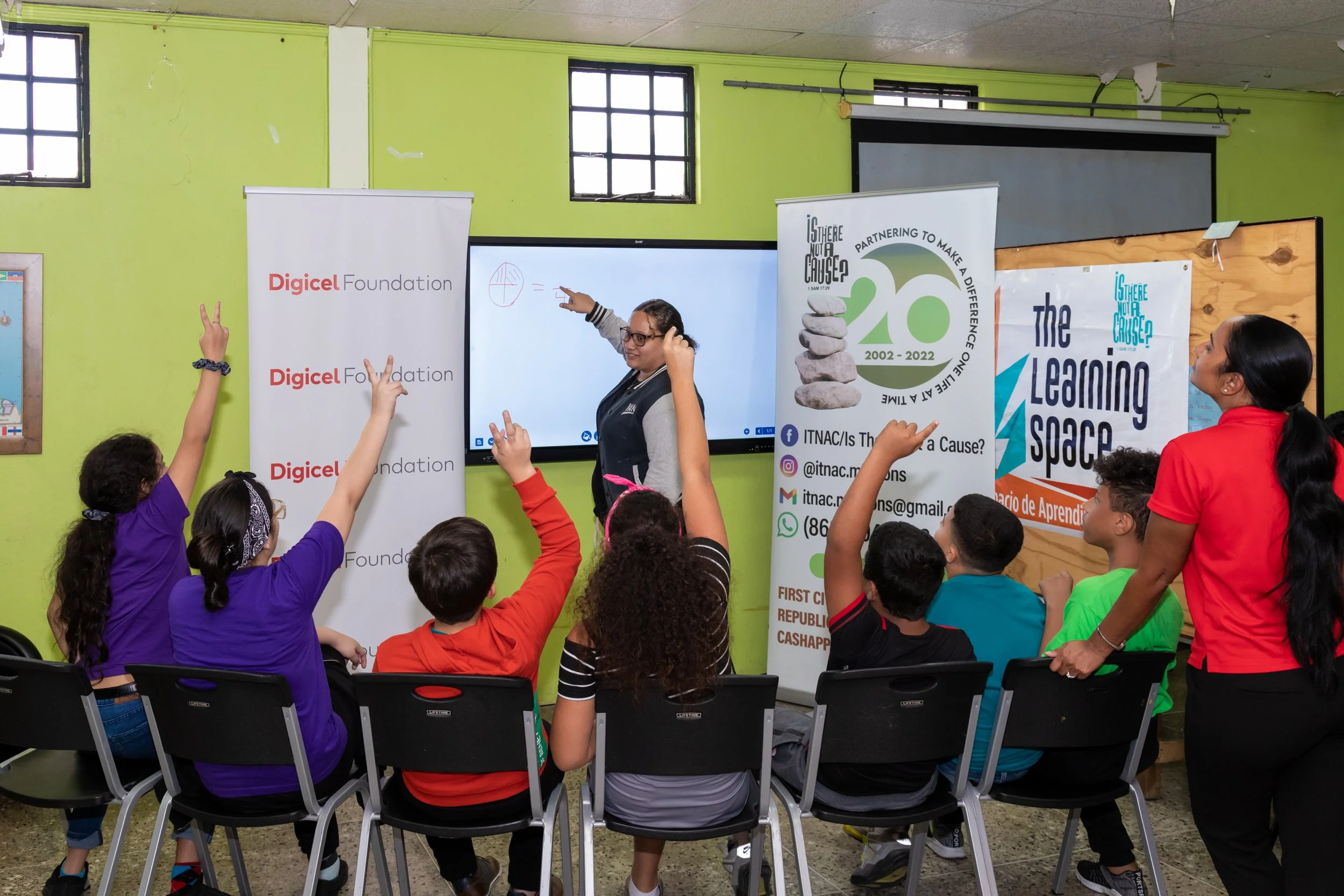 Children from the migrant community show excitement about learning as their teacher demonstrates a lesson using the new smart board installed by the Digicel Foundation in the learning space at ITNAC’s The Love Centre.