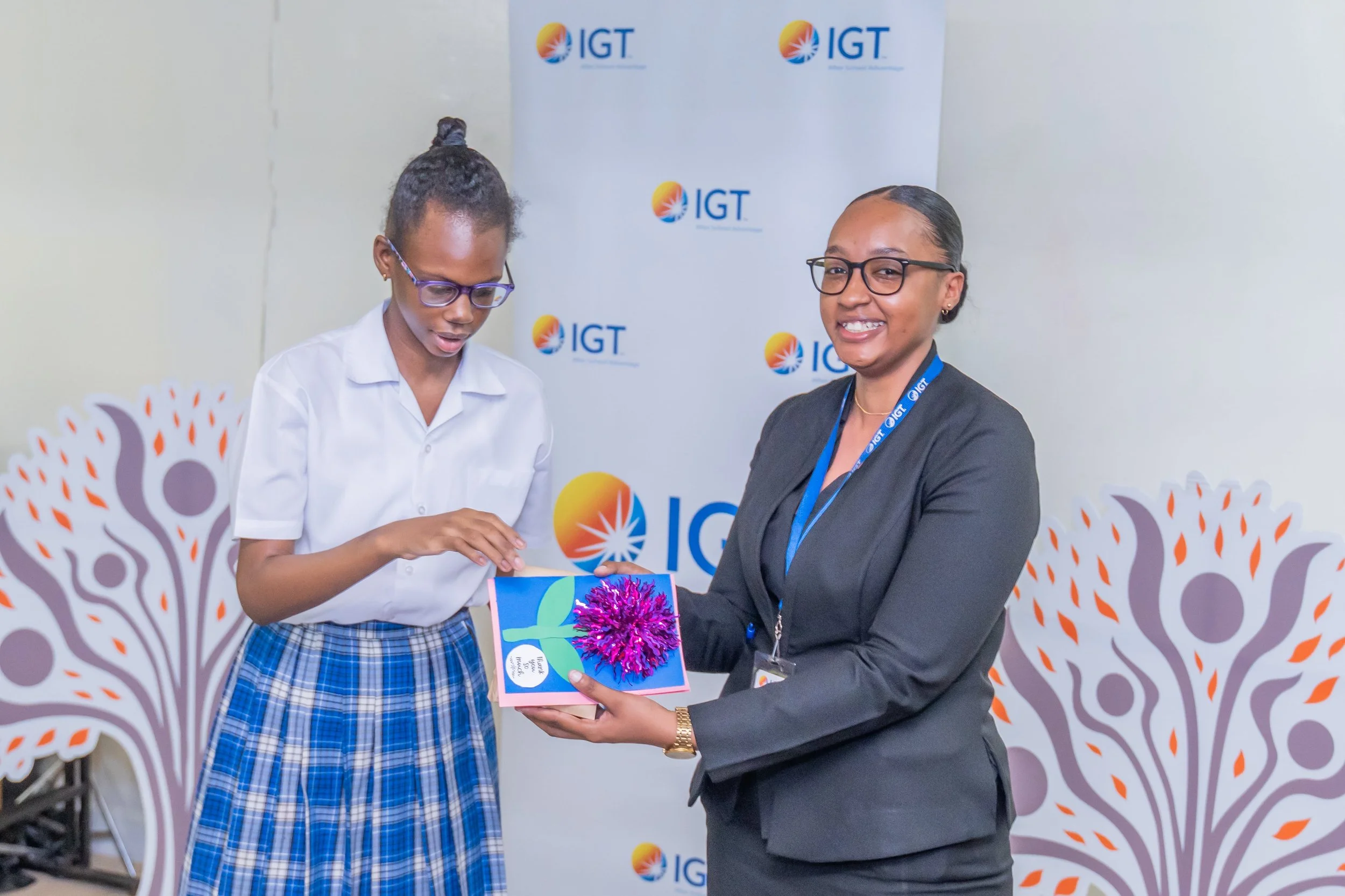  A student presents Chelsea Alleyne, IGT Administrative Assistant, with Thank You token for IGT’s support of the Immortelle Children’s Centre for Special Education. 