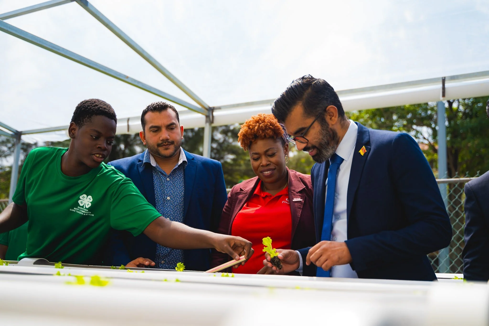 L-R) Isiah Daniel from the 4H Club shares his expertise on hydroponics farming with Minister in the Ministry of Agriculture, Land and Fisheries Mr. Avinash Singh; Head of Operations at Digicel Foundation Ms. Cindyann Currency, and MP for Barataria/ San Juan Mr. Saddam Hosein.