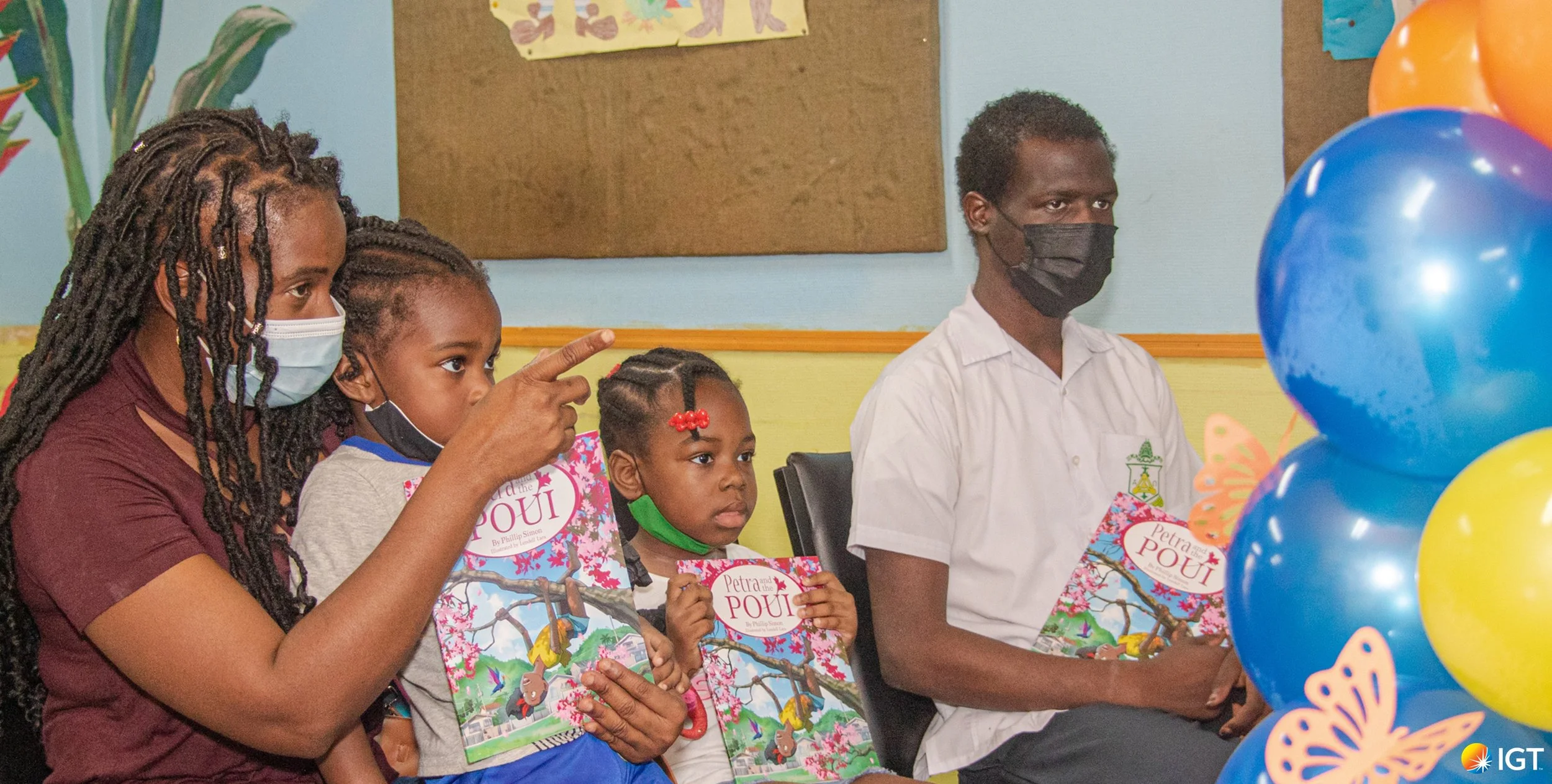 Jaden (right), a patient of the pediatric oncology clinic, sits with his mum and younger siblings enjoying the virtual storytelling session coordinated by the IGT ASA Programme and JBF. They each received a signed copy of the local children’s book, Petra and the Poui written by Phillip Simon.