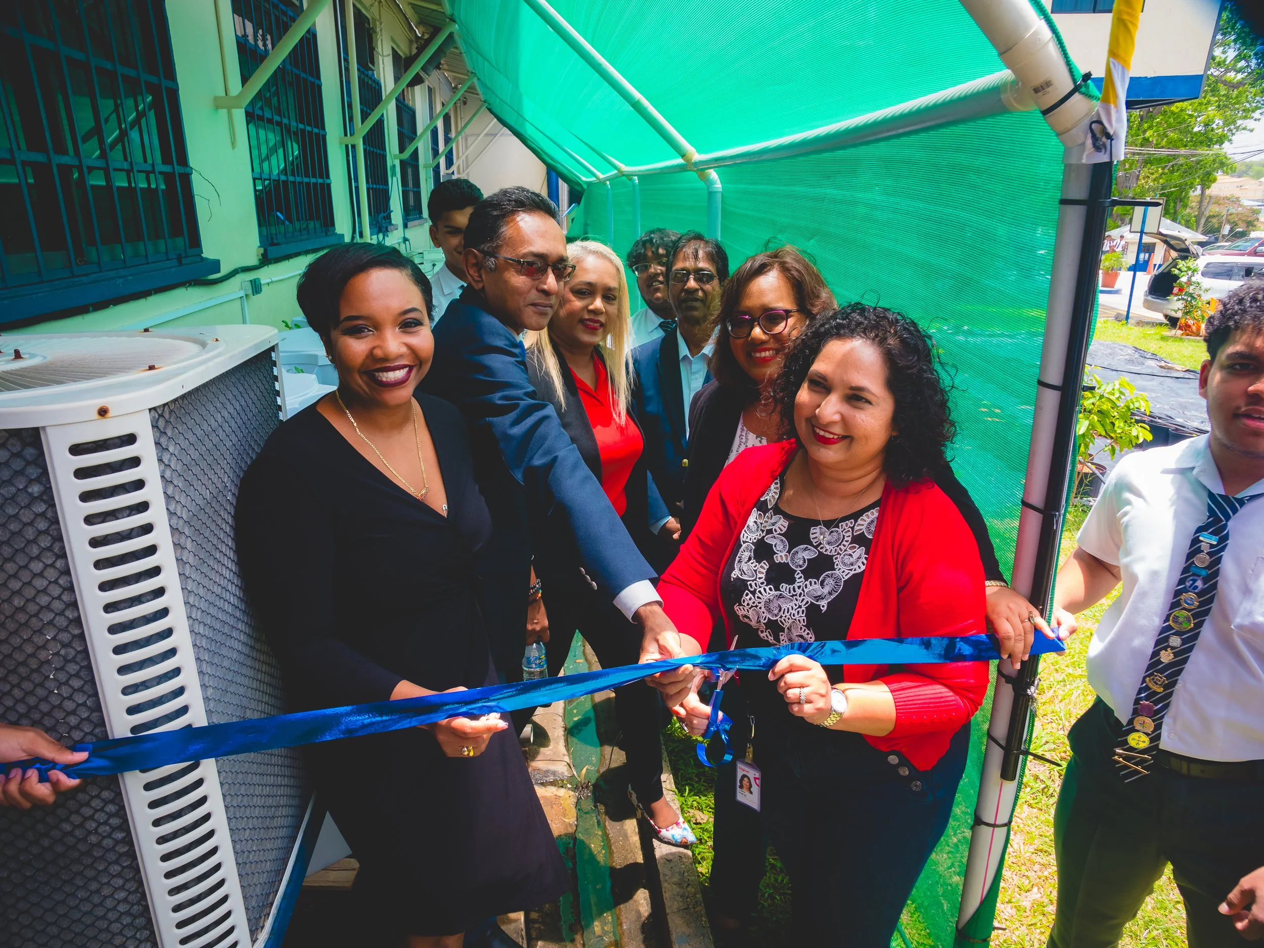 Digicel Foundation Board Director Trijata Maraj (right) and Shell T&T Performance and Social Investment Adviser Ryssa Brathwaite (left) cut the ribbon to officially launch the Naparima College EPIC project alongside other project stakeholders.