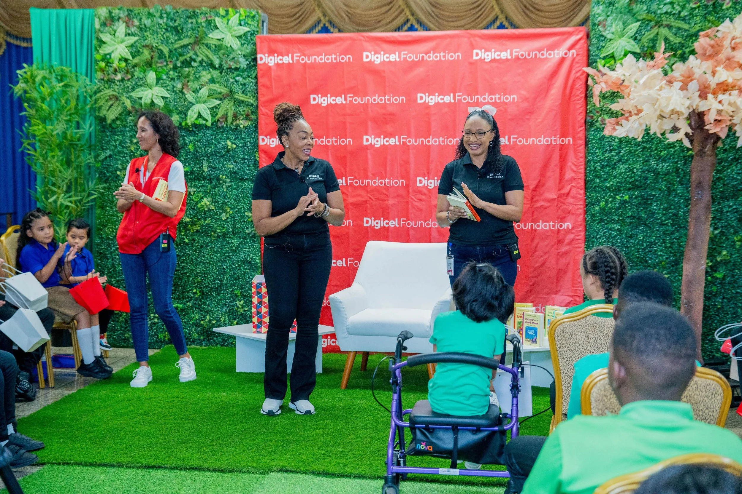Digicel Foundation CEO Penny Gomez leads the students in cheering on their storyteller, Digicel Foundation Director Romona Boiselle-Ramono (far right), and their translator, Naidelyn Rojas Figueroa (far left).