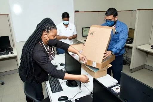  IGT volunteers Dena Bartholomew (Software Test Technician), Crystal Rodney (Jr Key Accounts Associate), and Varun Bhageraty (Draw Coordinator) complete installation of desktop computers at Cotton Tree Foundation. 