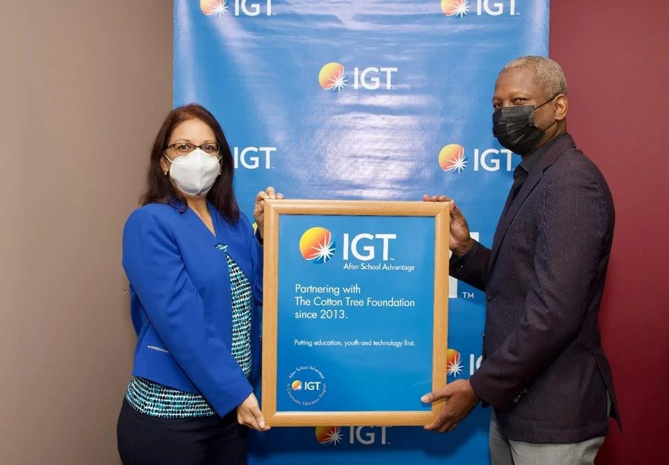(L-R) Cotton Tree Foundation Executive Director Sita Persad and IGT Deputy Country Manager Dexter W. Thomas display a framed poster commemorating the partnership between The Cotton Tree Foundation and IGT through IGT’s After School Advantage programme, which began in in 2013.