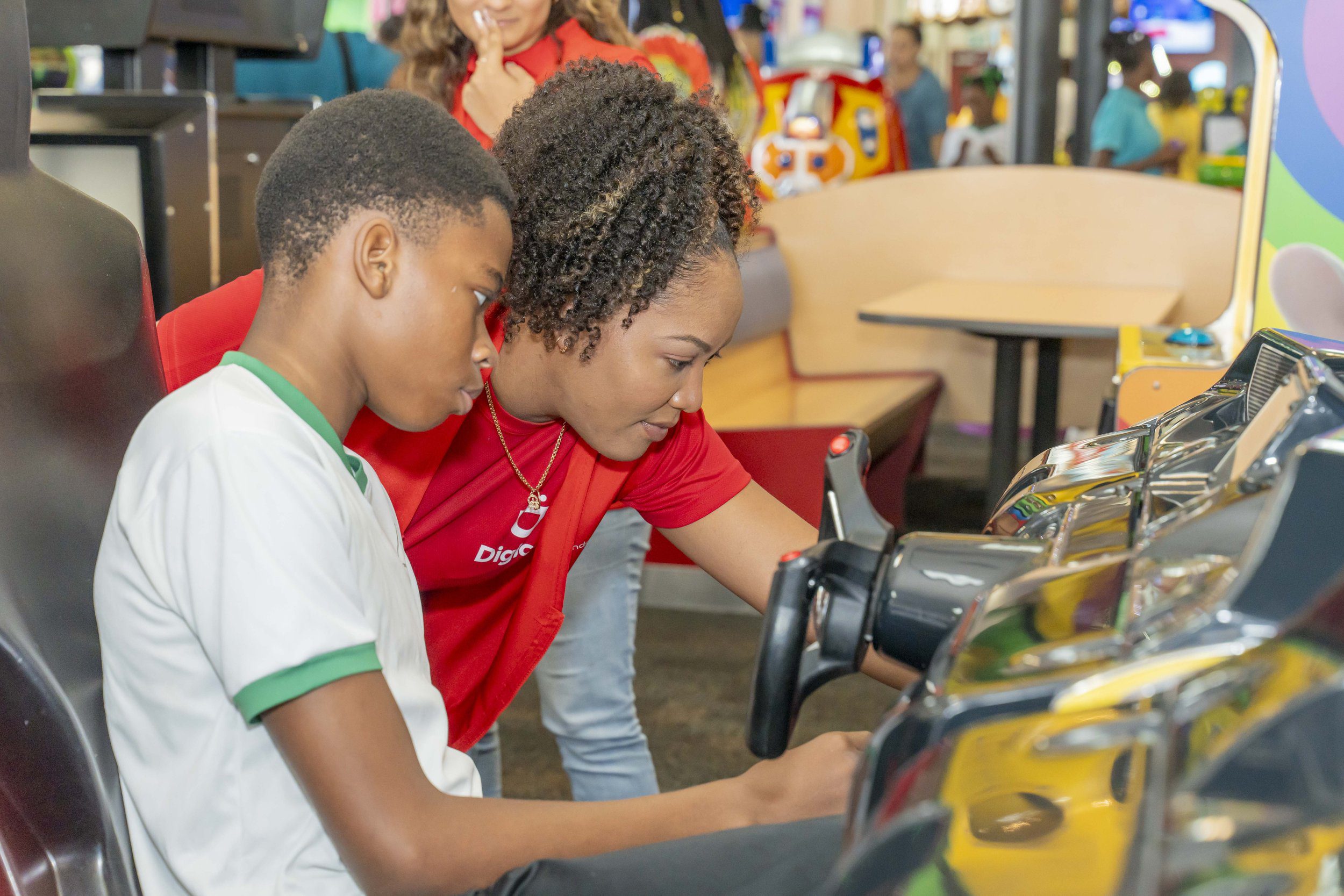  Digicel volunteer   Lou-Anne Joseph, Training Executive - Digicel Learning and Development, helps this youngster get the game going. 