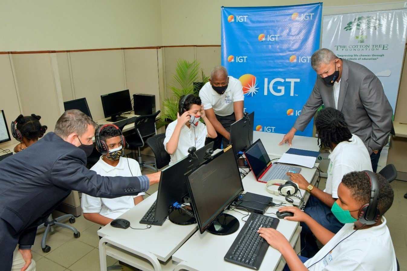 (L-R): Engaging with the Cotton Tree Foundation kids while they learn alongside their regional compatriots are Mr. Brendan Hames, IGT Caribbean Regional Director, Deputy Country Manager Mr. Dexter W. Thomas and IGT Country Manager Mr. Roger Bolai at the 2022 IGT Coding and Robotics Rock! Camp.