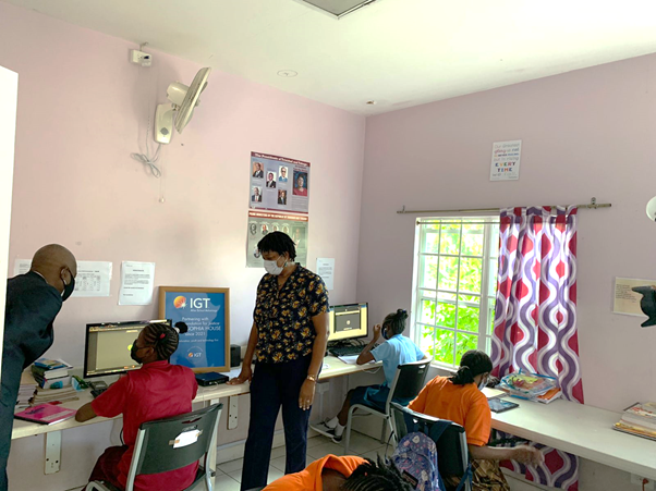 Photo 5- (From Left) IGT’s Deputy Country Manager- Dexter W. Thomas and Centre Coordinator, Ms Beverly John both assist a child during her online schoolwork.