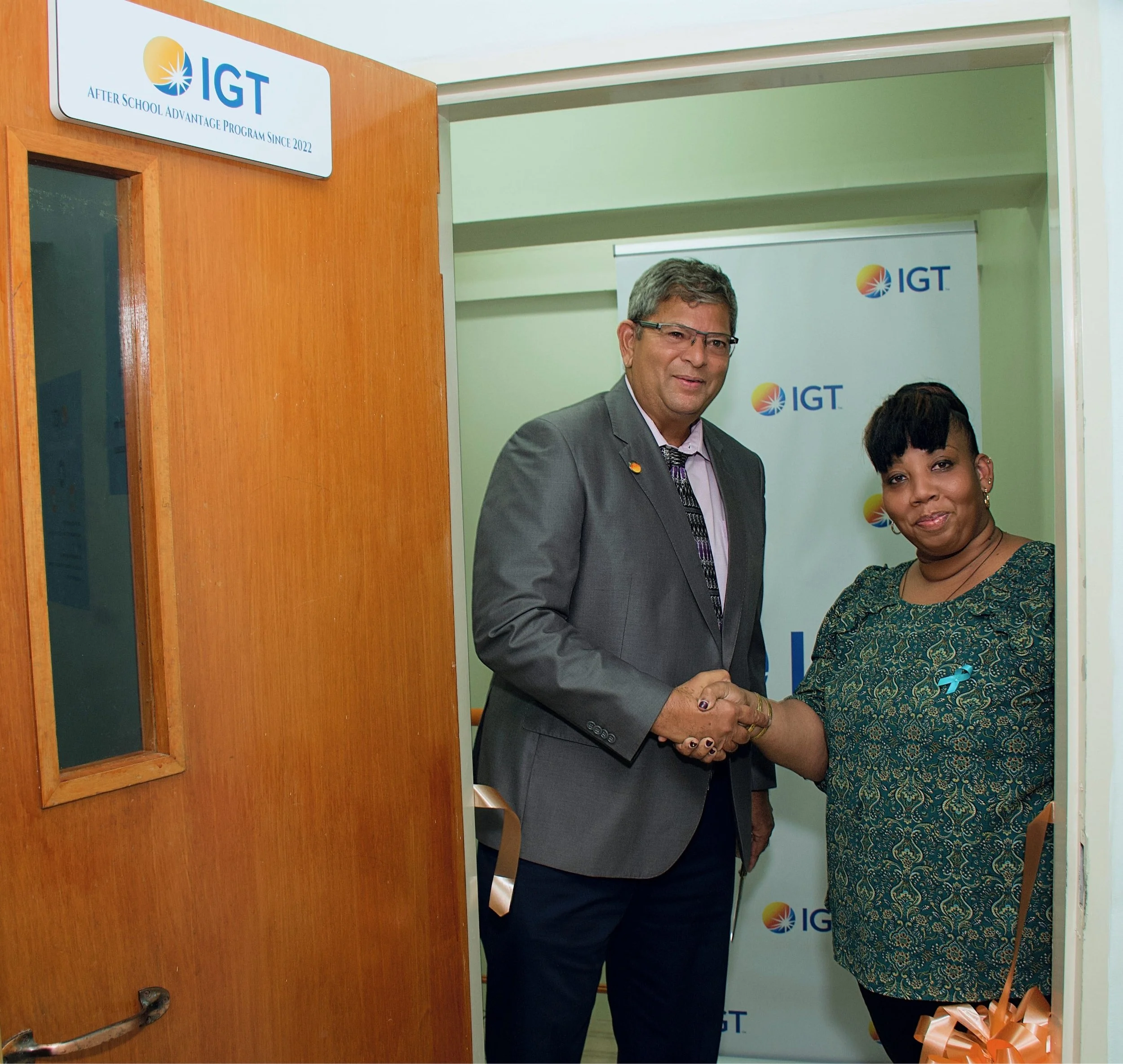 IGT Country Manager Roger Bolai exchanges a celebratory handshake with Credo Foundation for Justice Administrator Dale Bartholomew at the launch of the 18th IGT ASA Centre in Trinidad and Tobago at Credo Home for Boys.